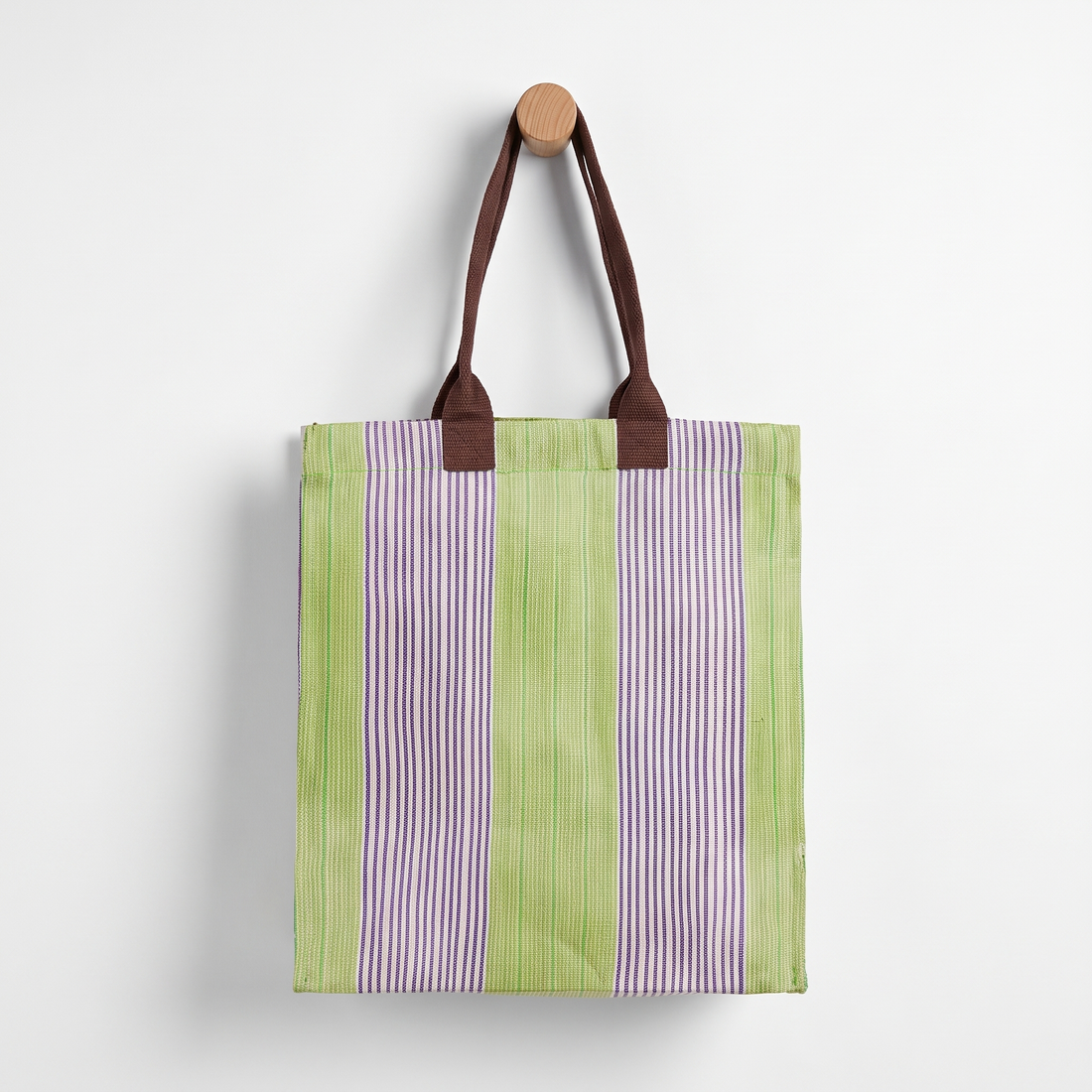 British Colour Standard Woven Market Tote - (Doge, Pearl & Grass) studio product photo hanging from a wooden wall hook on a…